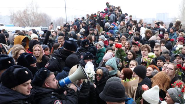 Un policía habla con megáfono a la multitud en el funeral del líder opositor ruso Alexei Navalny