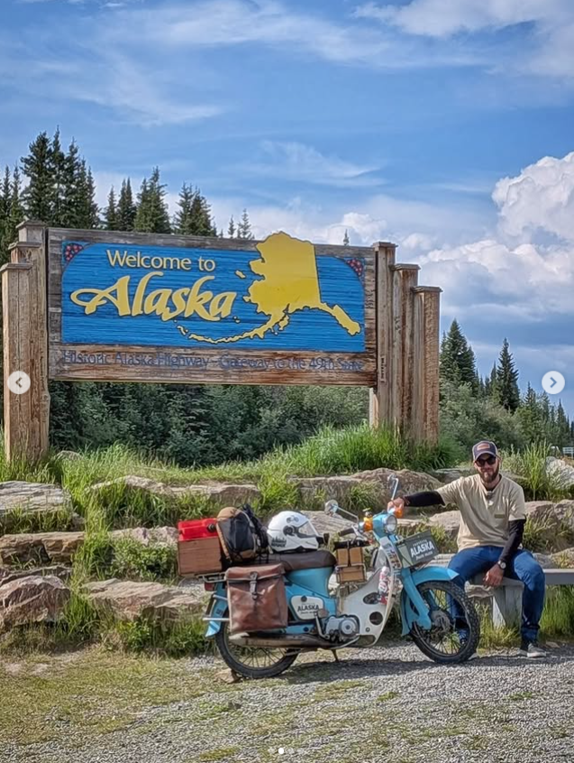 a man sitting on a bench next to a motorcycle
