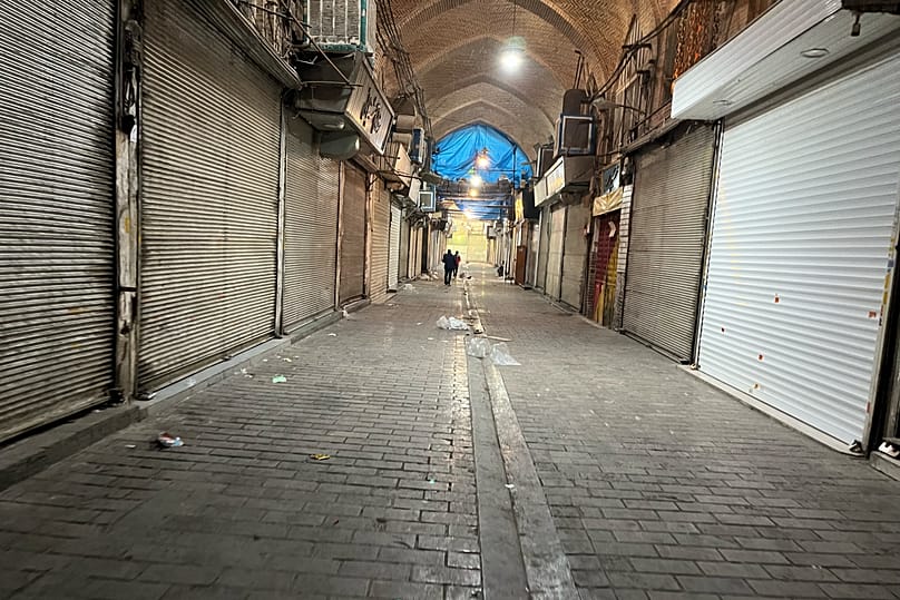 Personas caminan mientras se cierran tiendas durante las protestas en el centenario bazar principal de Teherán, 6 de enero de 2026.
